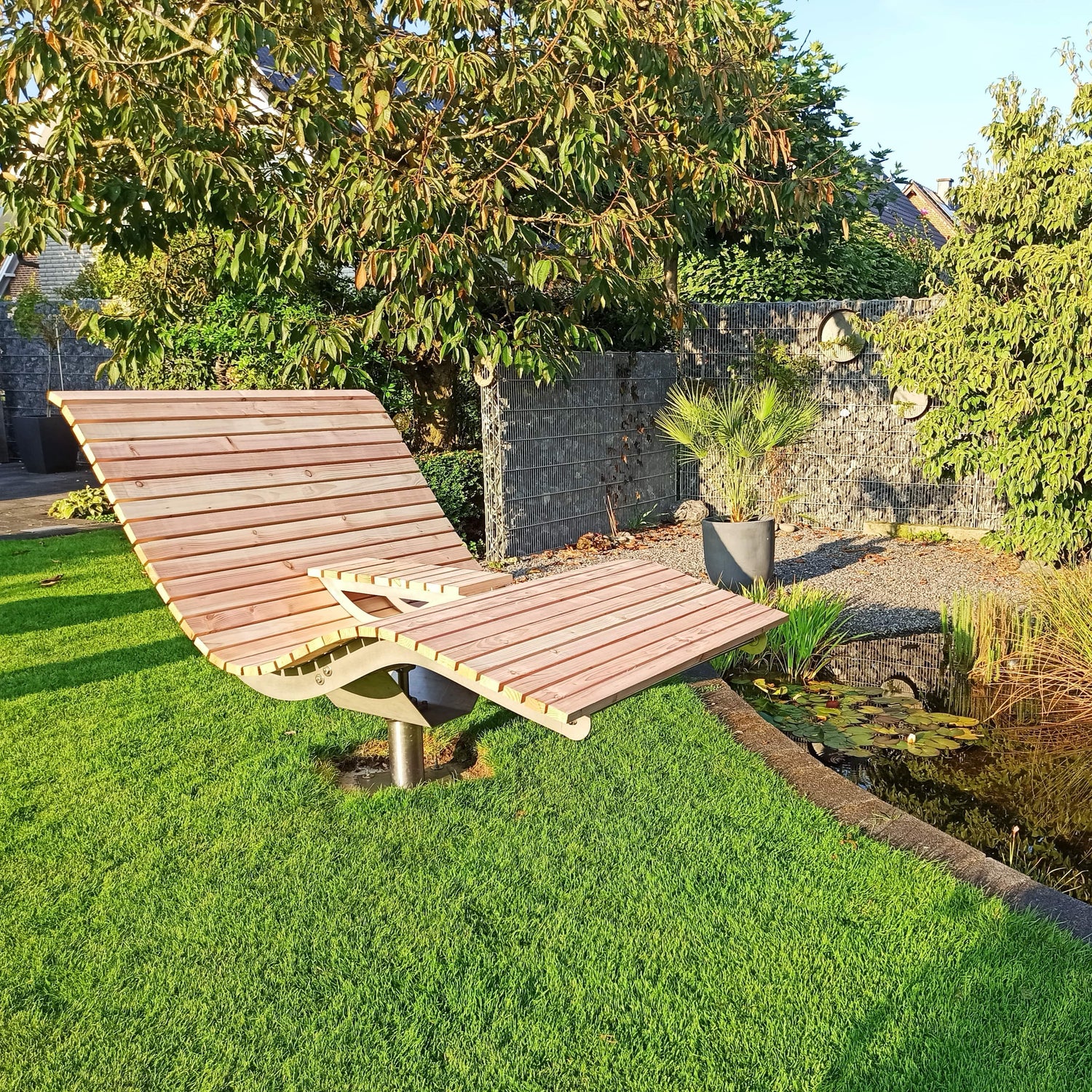 Ein Drehbares Waldsofa in einem Garten mit Teich bei Sonnenschein